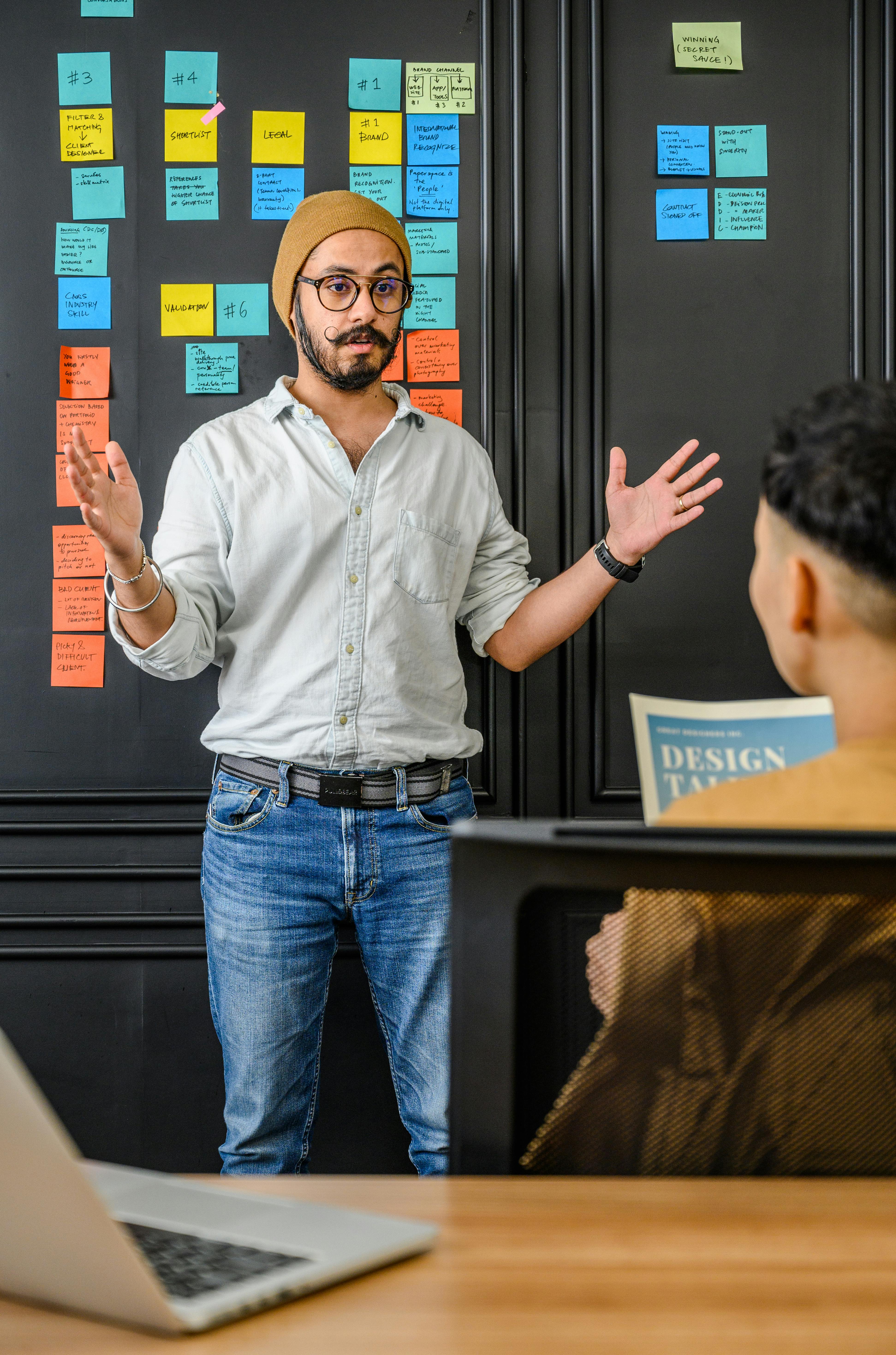 A bearded man discussing ideas with colleagues in an office setting.